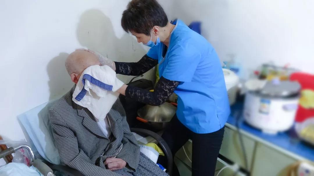 護(hù)理員在為老人清潔面部和手部.jpg